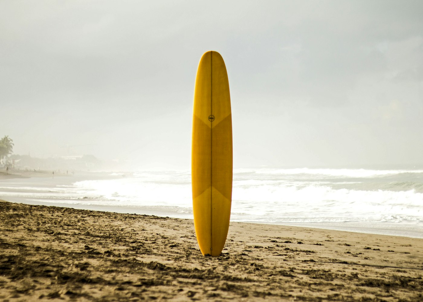 Planche de surf plantée dans le sable au petit matin